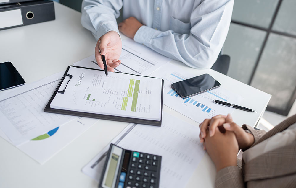 Zwei Personen sitzen am Tisch und besprechen Dokumente.