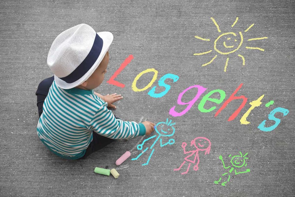 Ein Kind sitzt auf dem Boden und malt mit Kreide